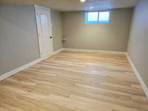 Basement with light wood-style floors, a textured ceiling, and recessed lighting