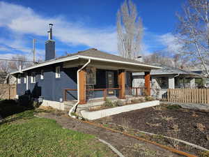 Bungalow-style home with a chimney, a porch, and brick siding
