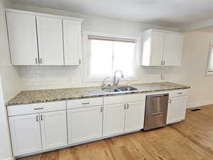 Kitchen featuring light stone counters, white cabinets, light wood-style floors, backsplash, and a textured ceiling