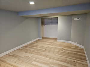 Finished basement featuring light wood-style floors, a textured ceiling, and recessed lighting