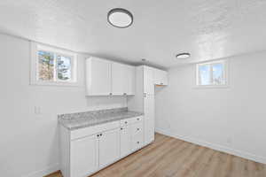 Laundry area featuring a textured ceiling and light wood-type flooring