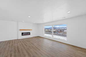 Unfurnished living room with a fireplace, light wood-style flooring, recessed lighting, and a mountain view