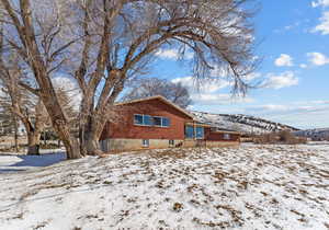 Snow covered back of property featuring a mountain view and brick siding