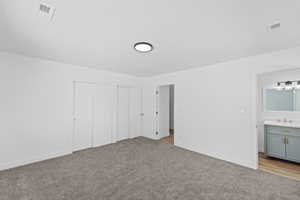 Unfurnished bedroom with multiple closets and light colored carpet