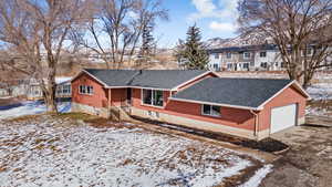 View of front of home with brick siding, roof with shingles, concrete driveway, and an attached garage
