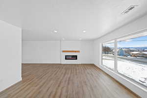 Unfurnished living room featuring a fireplace, light wood-type flooring, recessed lighting, and a mountain view