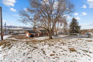 Yard layered in snow featuring a patio area and a mountain view