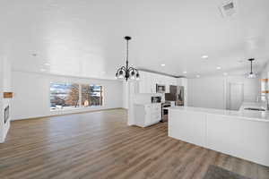 Kitchen featuring white cabinetry, stainless steel appliances, light wood-style floors, a peninsula, and open floor plan
