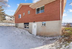 Snow covered property featuring brick siding
