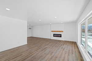 Unfurnished living room with a fireplace, light wood-style flooring, and hanging lights