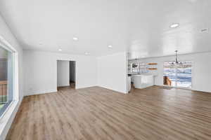 Unfurnished living room featuring light wood-style floors and a chandelier
