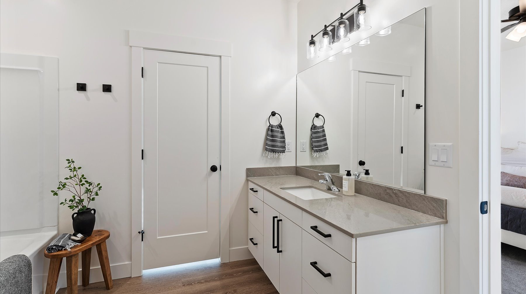 Full bath featuring ensuite bathroom, vanity, a garden tub, and dark wood-type flooring