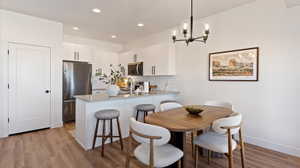 Kitchen with white cabinetry, stainless steel appliances, tasteful backsplash, a peninsula, and a breakfast bar