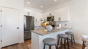 Kitchen featuring a breakfast bar, white cabinets, stainless steel appliances, a peninsula, and recessed lighting
