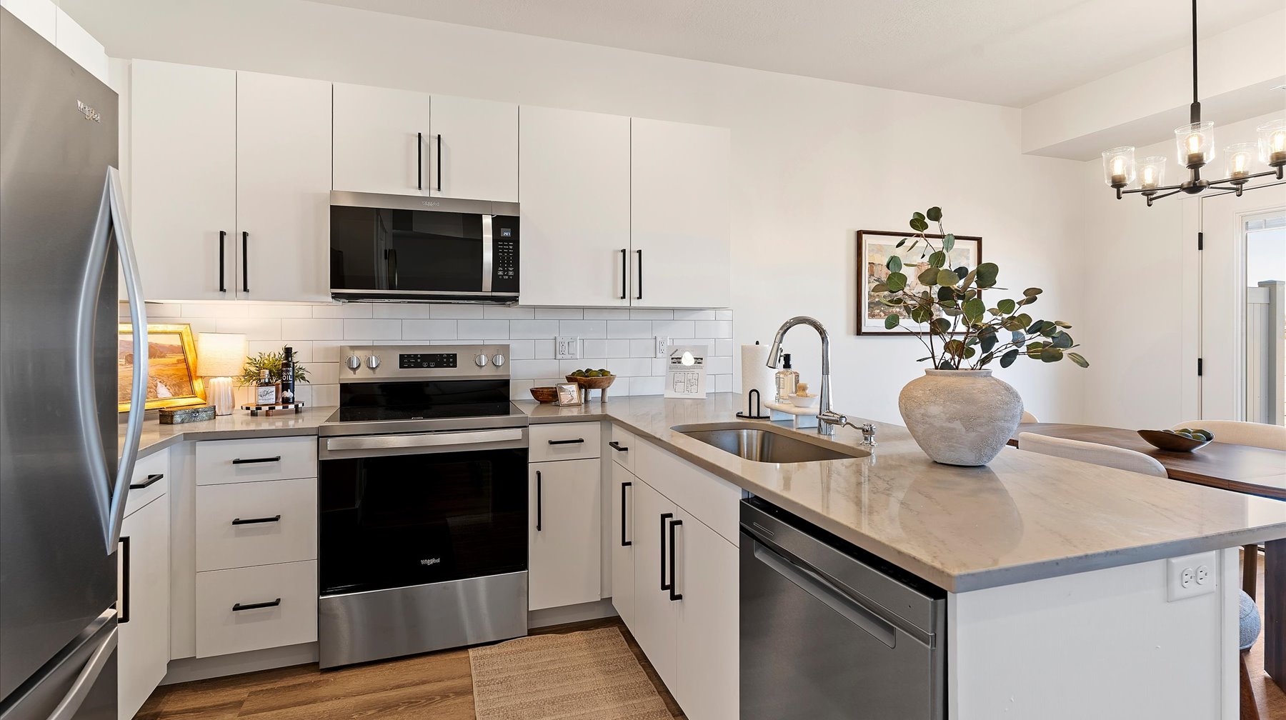 Kitchen with a peninsula, stainless steel appliances, light stone counters, and white cabinetry