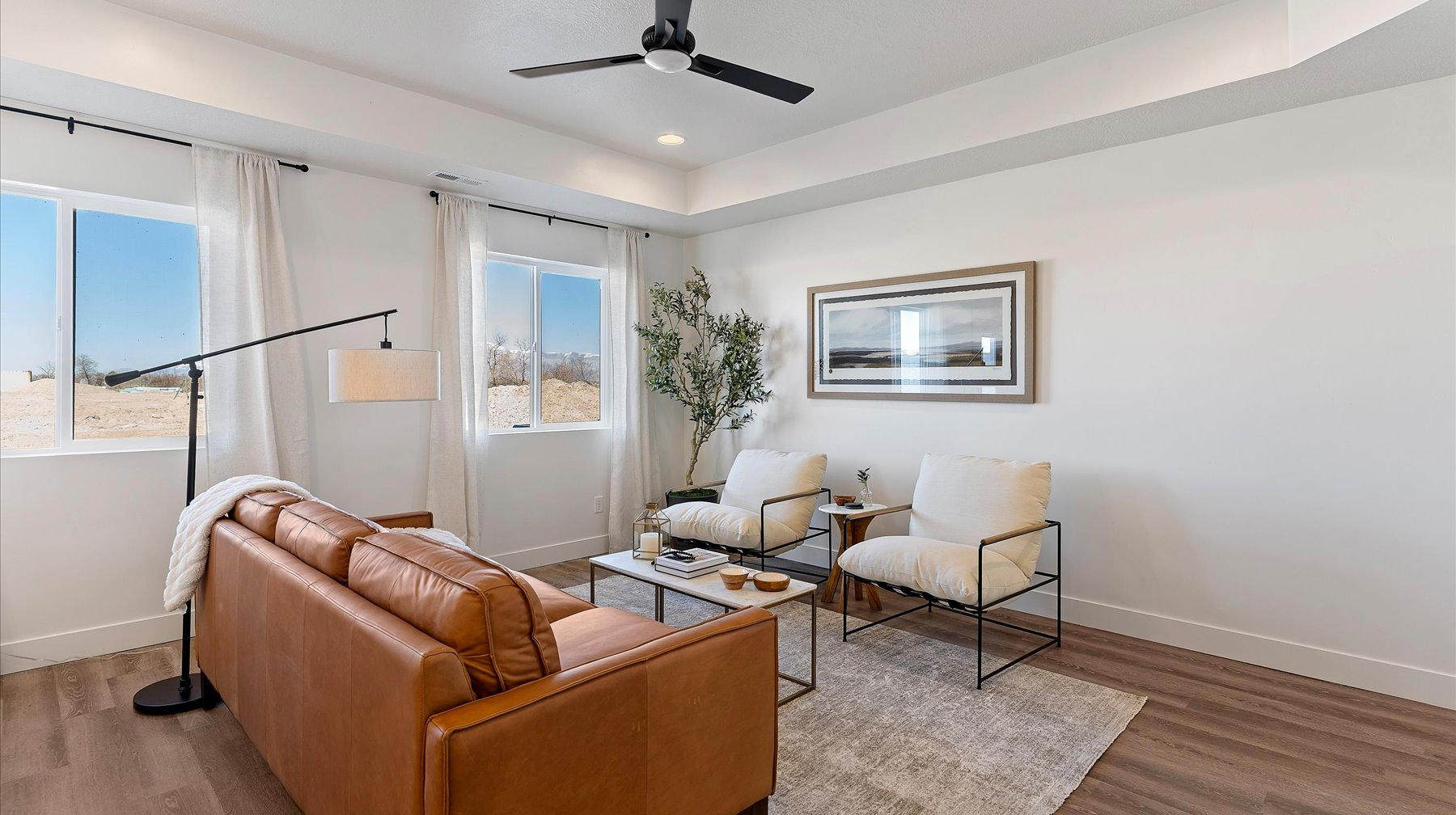 Living area with ceiling fan, wood finished floors, a raised ceiling, and recessed lighting
