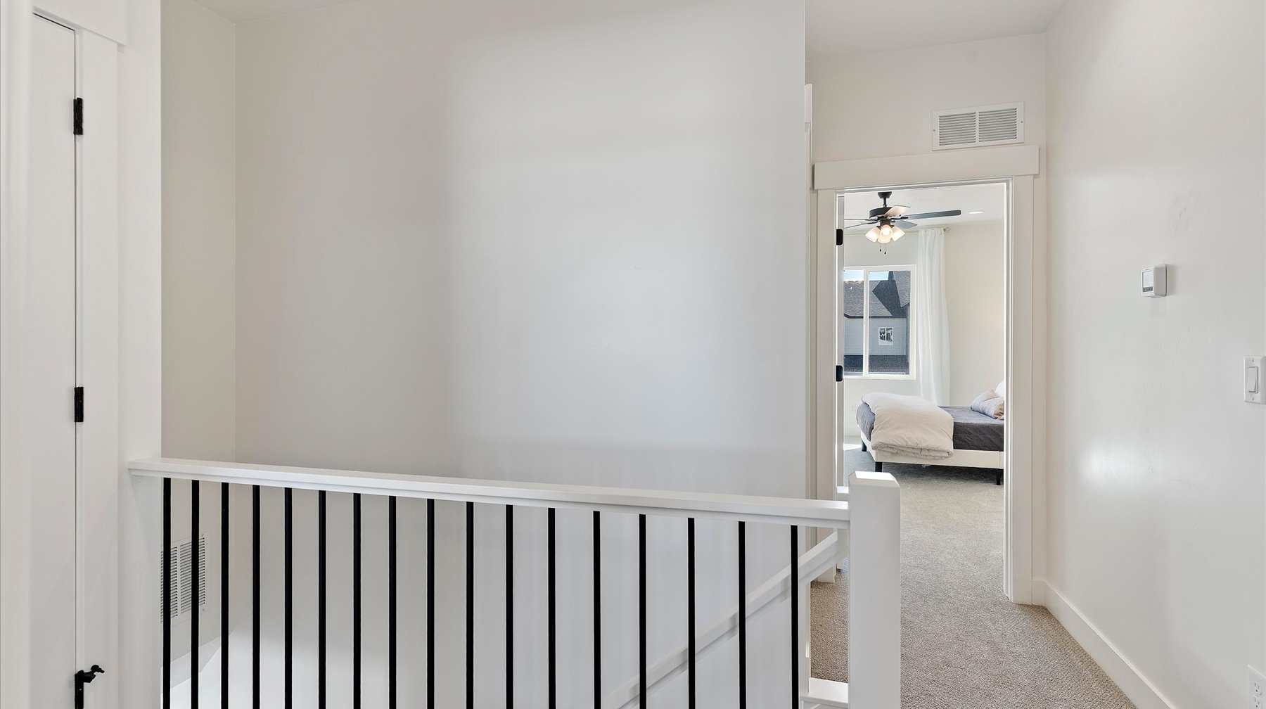 Hallway featuring light colored carpet and baseboards