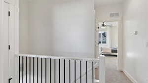 Hallway featuring light colored carpet and baseboards