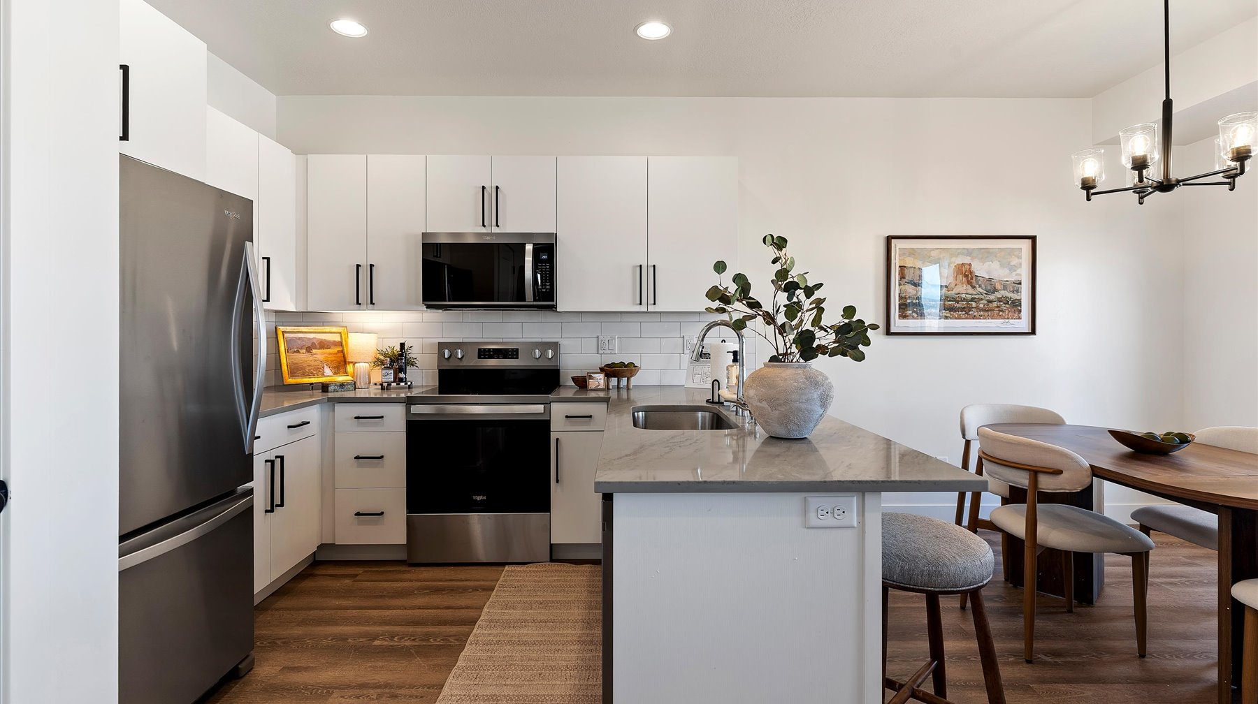 Kitchen featuring a peninsula, stainless steel appliances, white cabinetry, and a breakfast bar