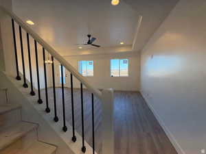 Stairway featuring wood finished floors, a ceiling fan, and suspended lighting
