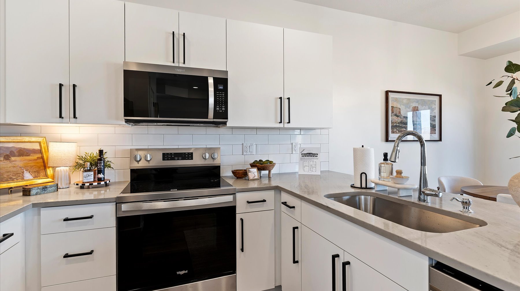 Kitchen with stainless steel appliances, white cabinets, light stone counters, and backsplash