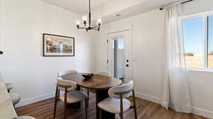Dining area featuring dark wood-style flooring and suspended lighting