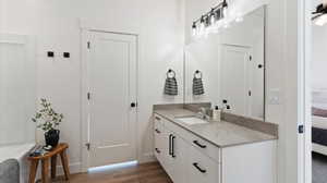 Full bath featuring ensuite bathroom, vanity, a garden tub, and dark wood-type flooring