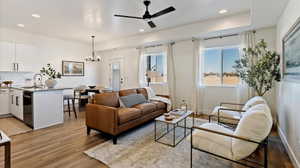 Living room with a ceiling fan, a chandelier, and light wood finished floors