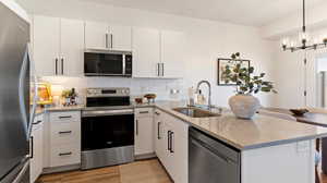Kitchen with a peninsula, stainless steel appliances, light stone counters, and white cabinetry