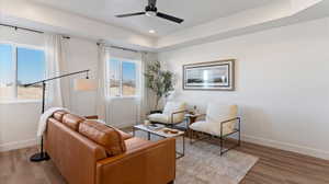Living area with ceiling fan, wood finished floors, a raised ceiling, and recessed lighting