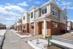 View of front facade featuring brick siding, a residential view, stucco siding, and board and batten siding