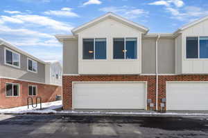 View of front facade featuring an attached garage, board and batten siding, and brick siding