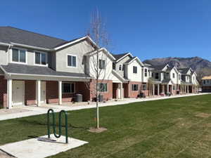 View of front facade with a porch, a front yard, a residential view, and brick siding