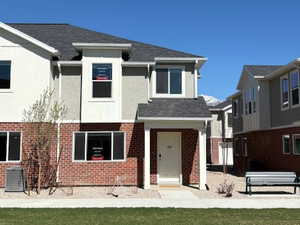 View of front of home featuring a front lawn, a shingled roof, and brick siding