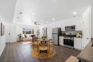 Kitchen with stainless steel appliances, white cabinets, dark stone countertops, and dark wood finished floors