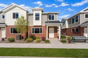 View of front of home with brick siding, board and batten siding, and a front yard