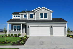 View of front facade with concrete driveway, covered porch, a garage, a shingled roof, and a front yard