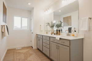Bathroom with double vanity, light wood finished floors, and recessed lighting