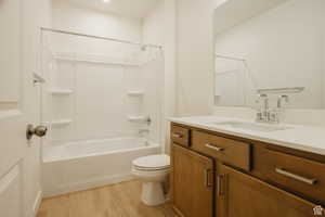 Full bath with vanity, light wood finished floors, and shower / bath combination