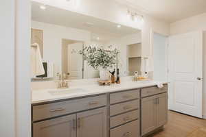 Full bath featuring double vanity and light wood finished floors