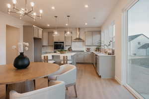 Kitchen with gray cabinetry, a center island, a kitchen breakfast bar, light wood-style flooring, and oven