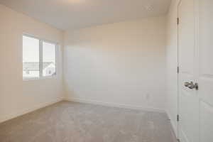 Unfurnished room featuring light carpet and baseboards