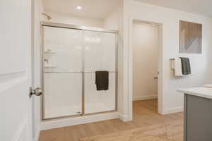 Bathroom featuring vanity, light wood-style flooring, and a stall shower