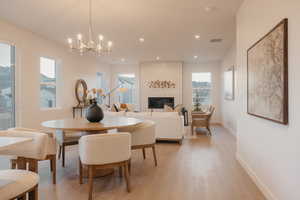 Dining area featuring light wood finished floors, a chandelier, and a fireplace
