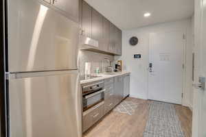 Kitchen featuring stainless steel appliances, light countertops, backsplash, light wood finished floors, and recessed lighting