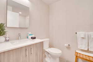 Half bathroom featuring tile walls, vanity, tile patterned floors, and recessed lighting