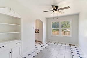 Spare room with arched walkways, a ceiling fan, and light floors