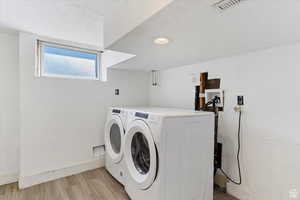 Laundry area featuring light wood-style flooring and washing machine and dryer