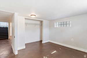 Unfurnished bedroom featuring finished concrete flooring and a closet