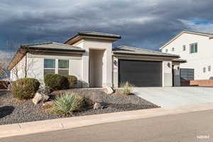Prairie-style home with a garage, concrete driveway, and stucco siding
